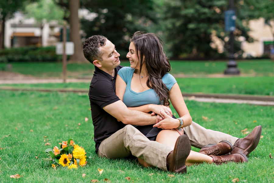 A fun couple lay in the grass in a park in Philadelphia.